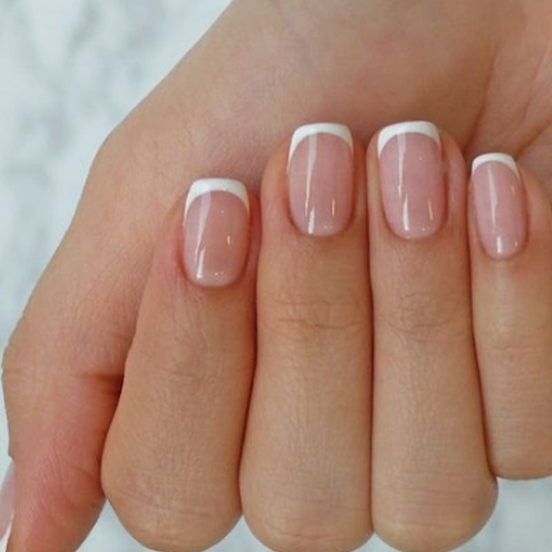 A hand with short square pink nails with a French tip design.