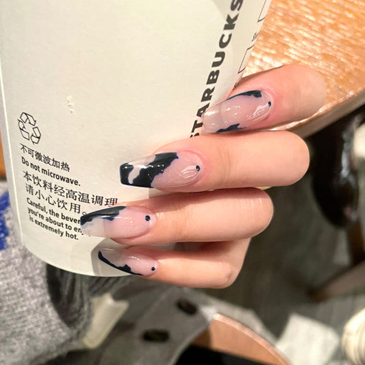 Hand holding a Starbucks cup with black and white nail design
