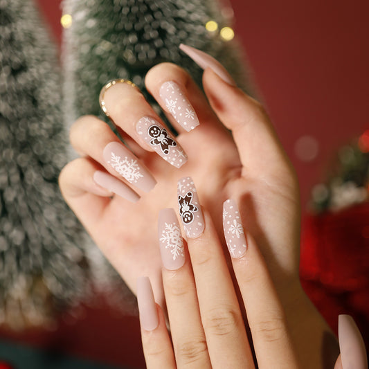 Close-up of a hand with decorative nails in front of a Christmas tree.