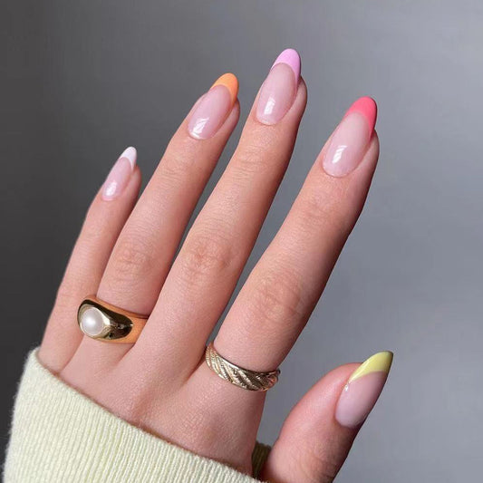Hand with colorful nail polish and gold rings on a gray background