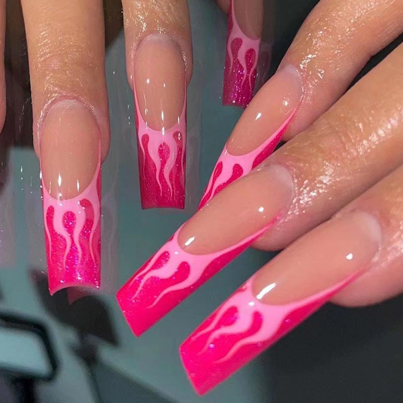 A set of pink press-on nails with flame accents, designed to be worn on fingernails.