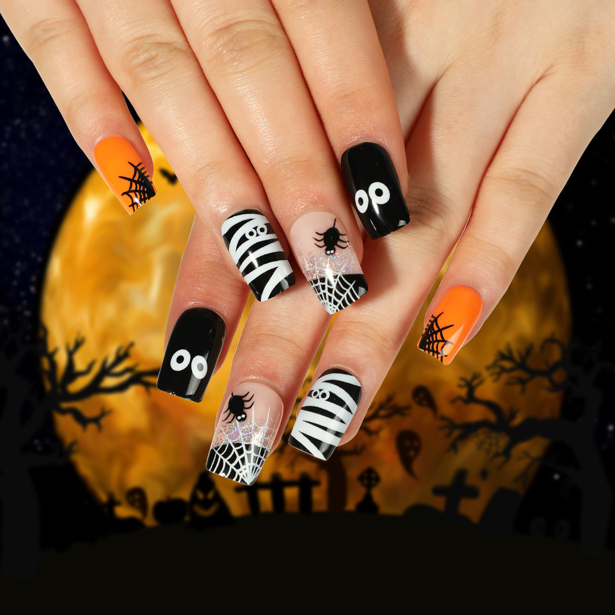A hand showcasing medium square orange press-on nails with black and white Halloween-themed designs, such as stripes and spider patterns, against a Halloween-themed background with a full moon and bats.