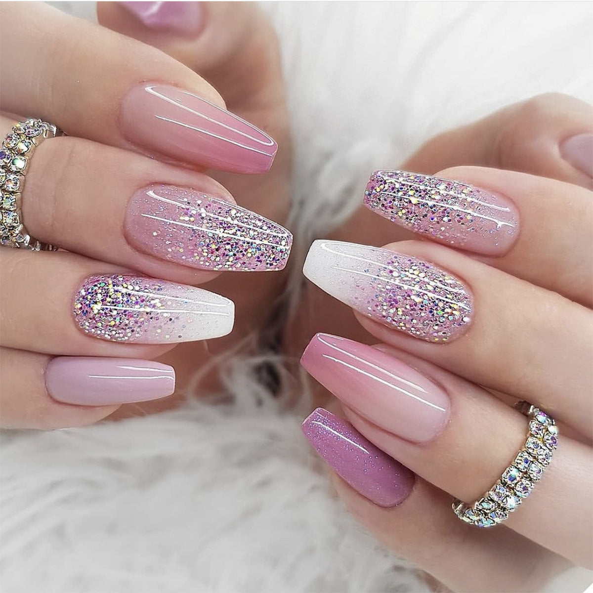 A pair of hands showcasing press-on nails with a medium coffin shape in a pink glitter design.