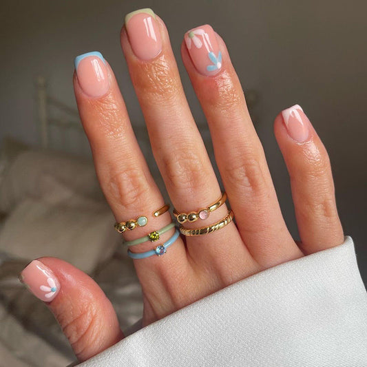 Hand with painted nails and multiple rings on a neutral background