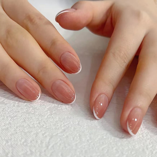 A close-up of a person's fingernails showcasing press-on nails with a French tip design, predominantly white with a natural-looking shade at the roots.