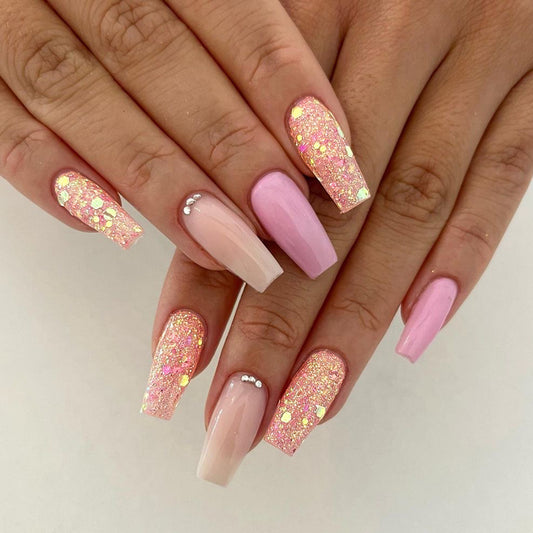 Close-up of hands with pink and glittery nails on a neutral background