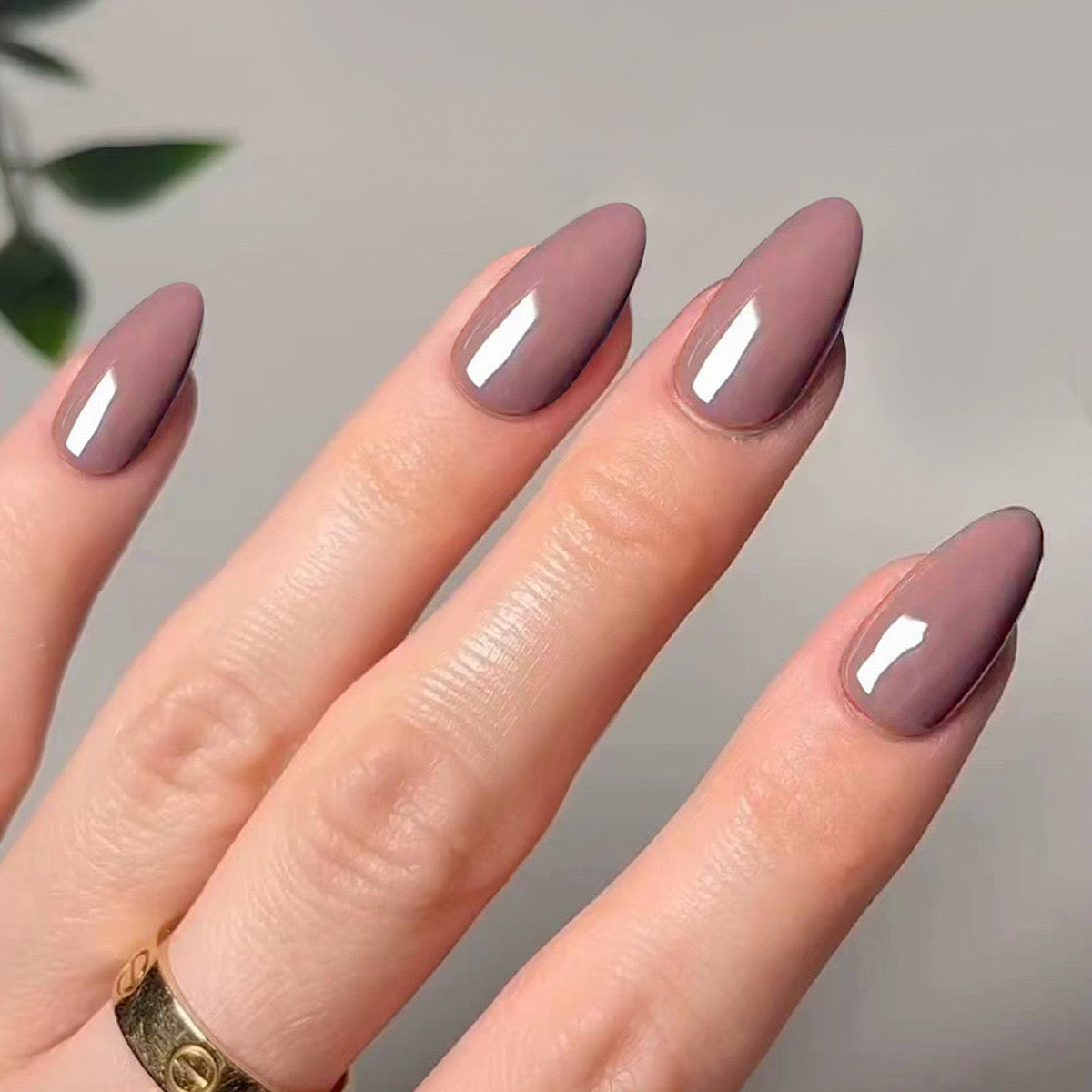 Hand with almond-shaped nails painted in a gradient of mauve and gray on a neutral background.
