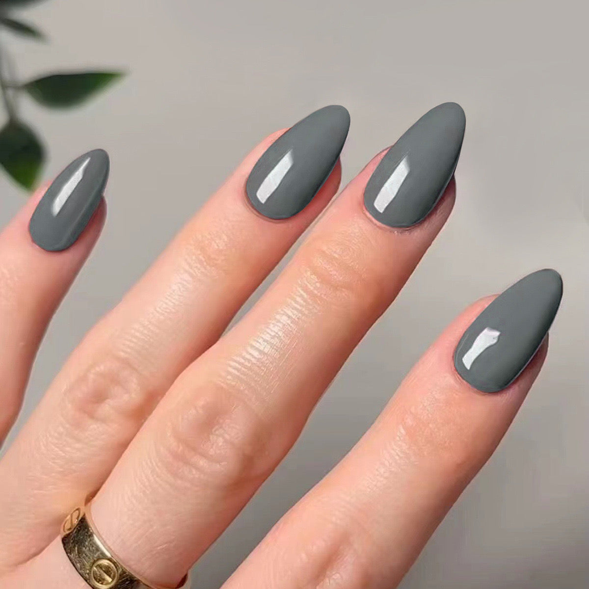 A set of charcoal gray press-on nails with a matte finish, displayed on a person's hand.