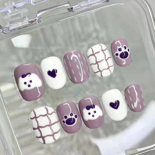 A set of purple press-on nails with cartoon-style puppy and heart designs.