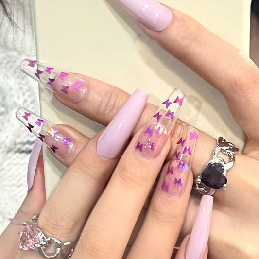 A set of long coffin-shaped nails with a purple color and star patterns.