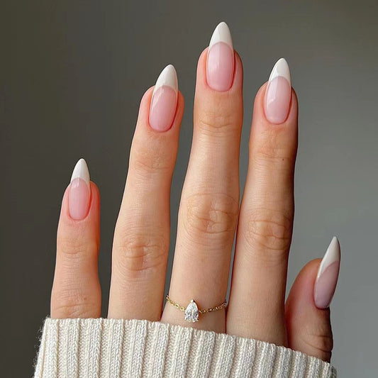 Close-up of a hand with pink and white nail polish wearing a gold ring on a neutral background