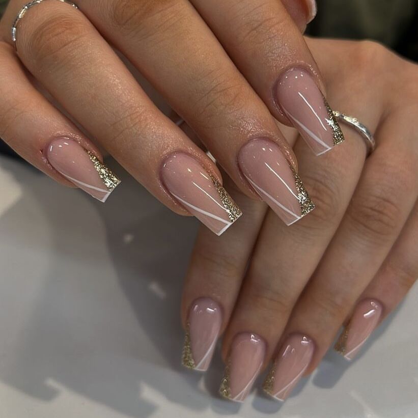 Close-up of hands with pink nail polish and gold accents on a neutral background