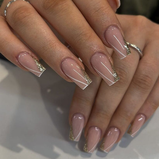 Close-up of hands with pink nail polish and gold accents on a neutral background