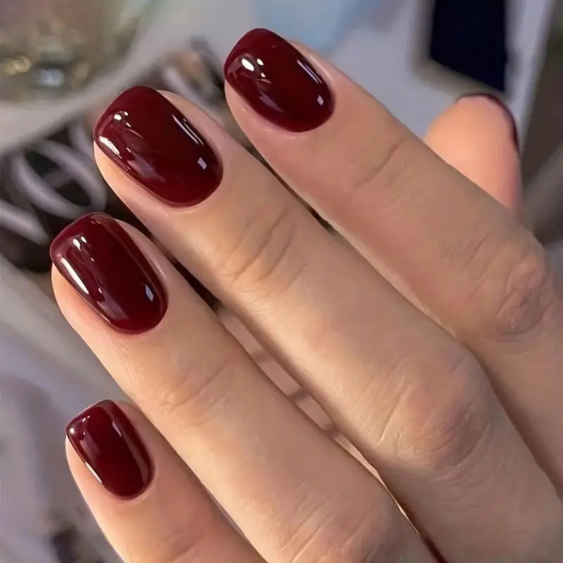 Close-up of a hand with dark red nail polish on a blurred background