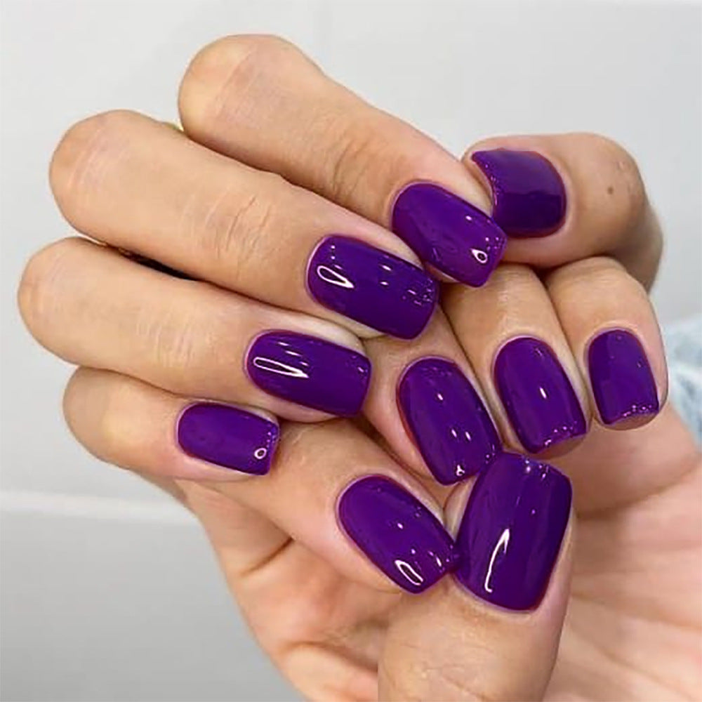 Hand with purple nail polish on a plain background