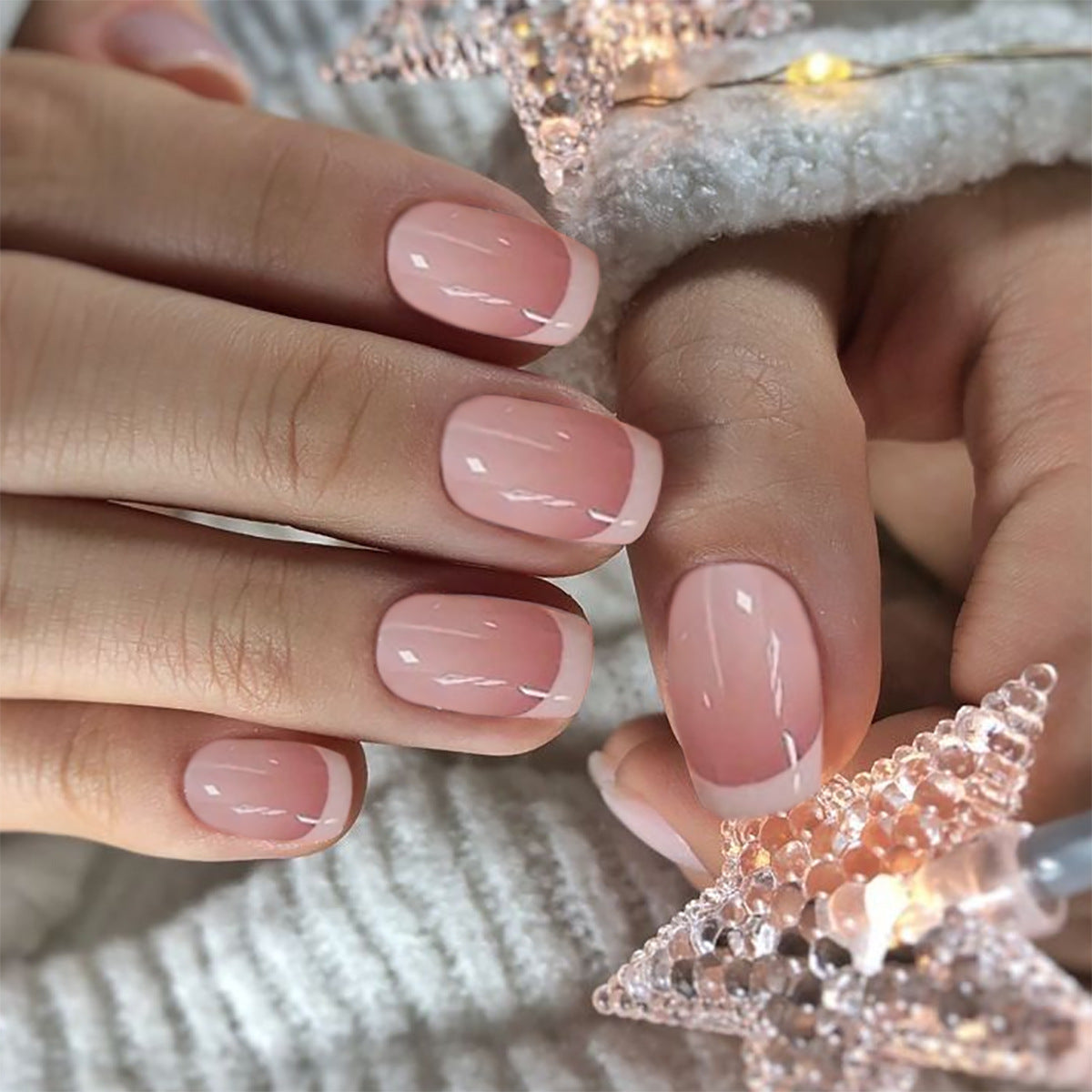 Close-up of hands with pink nail polish against a soft, blurred background