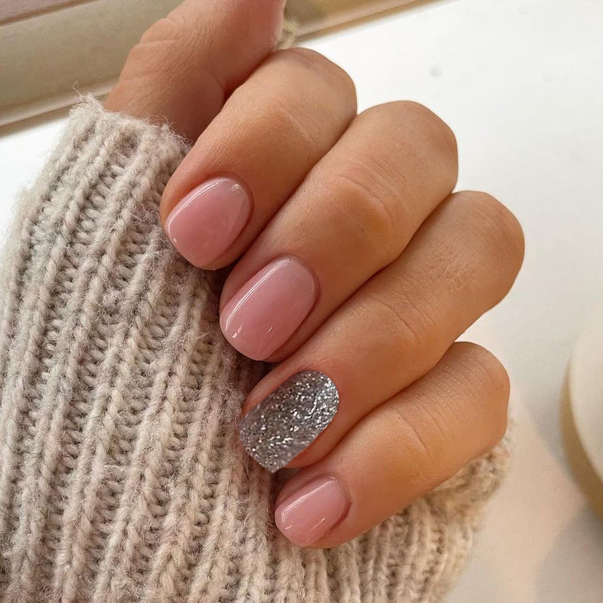 Hand with pink nail polish and a glittery silver nail holding a textured beige fabric.