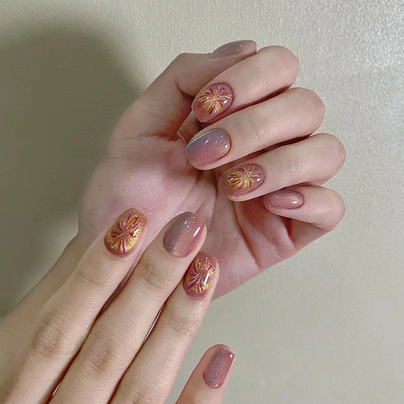 Hand with pink and gold floral nail design on a plain background