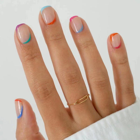 A person's fingers showcasing press-on nails with a beige base and colorful, rainbow outline designs.