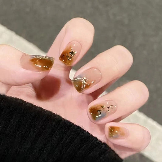 A person's hand with medium-sized square-shaped brown glossy press-on nails.