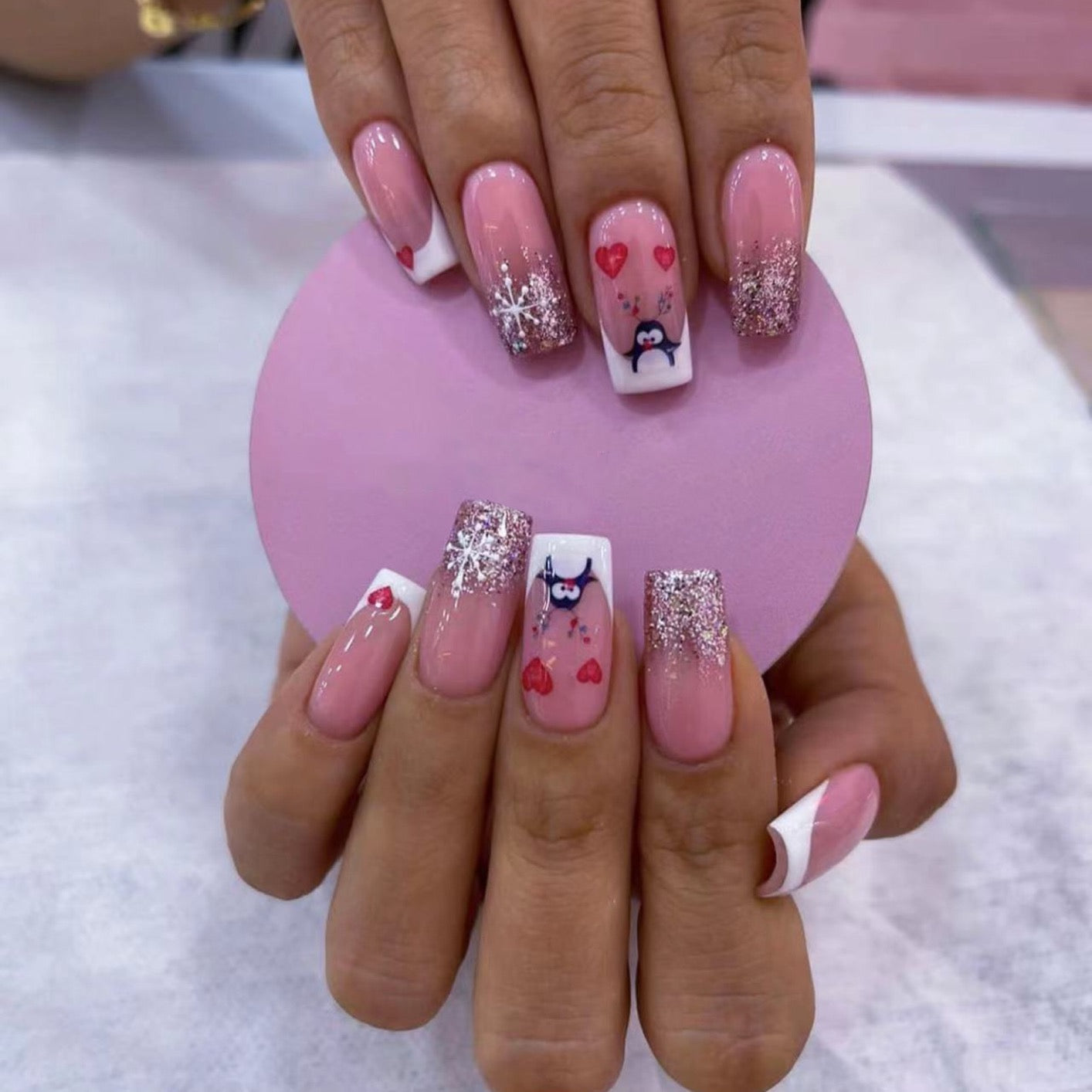 Hand with pink nail art holding a heart-shaped mirror