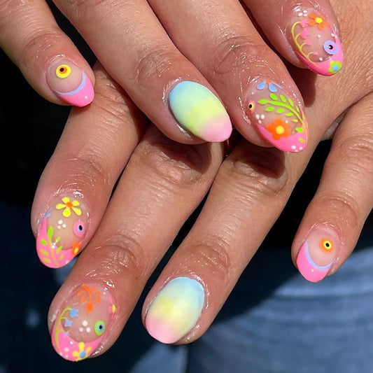 A set of multicolored press-on nails featuring an ombre design with a mix of pink, yellow, and blue shades, adorned with small floral and geometric patterns.
