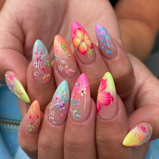 A hand with almond-shaped nails painted in a multicolor floral design with a glossy finish.