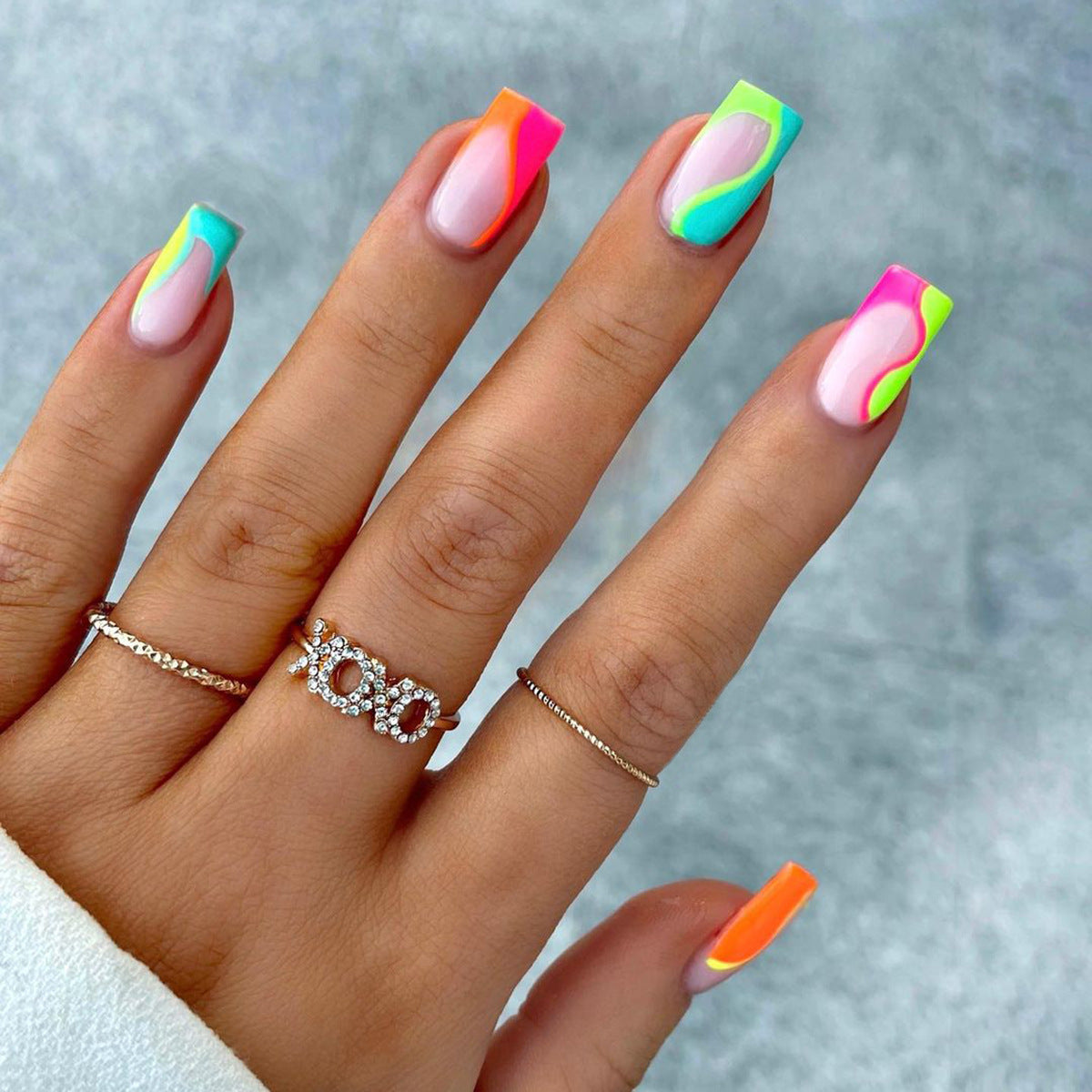 A set of long square-shaped press-on nails featuring a multicolor groovy design with orange, pink, green, and blue colors.