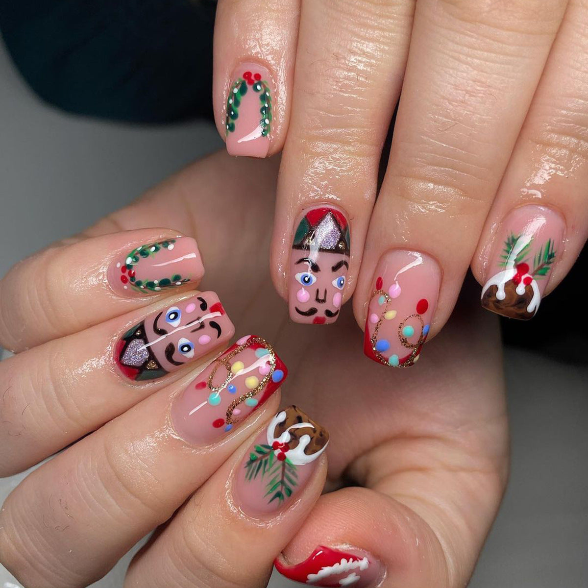 A set of multicolored press-on nails featuring a holiday-themed design with a character and Christmas decorations.