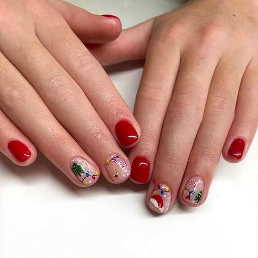 A pair of hands showcasing press-on nails with a multicolor holiday design, including Christmas-themed decorations on a clear background.