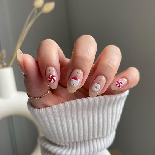 Nails with Christmas-themed designs held by a person wearing a white sweater.