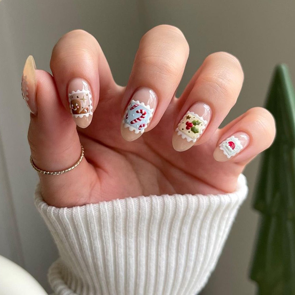 Hand with Christmas-themed nail art wearing a white sleeve.