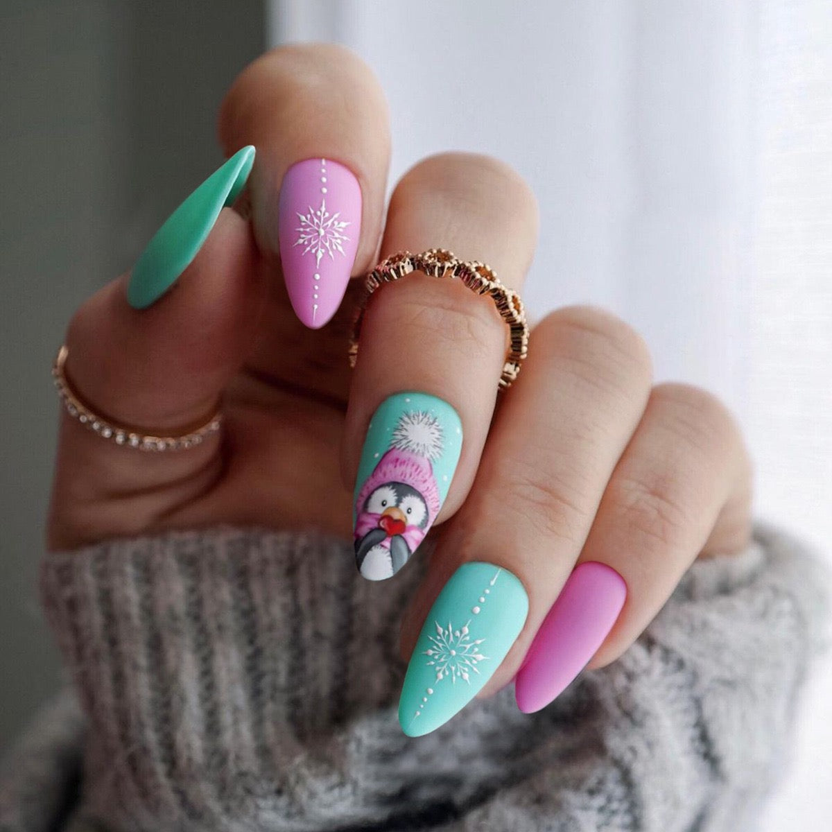 Close-up of a hand with colorful nail art featuring a penguin design.
