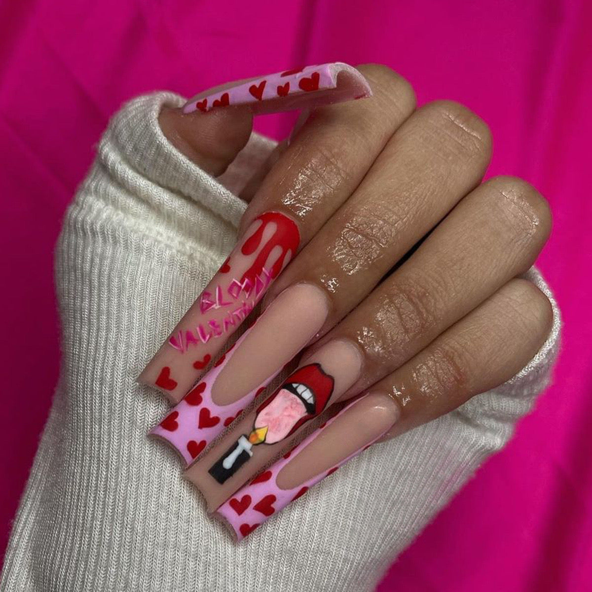 Hand with pink and red nail art on a pink background