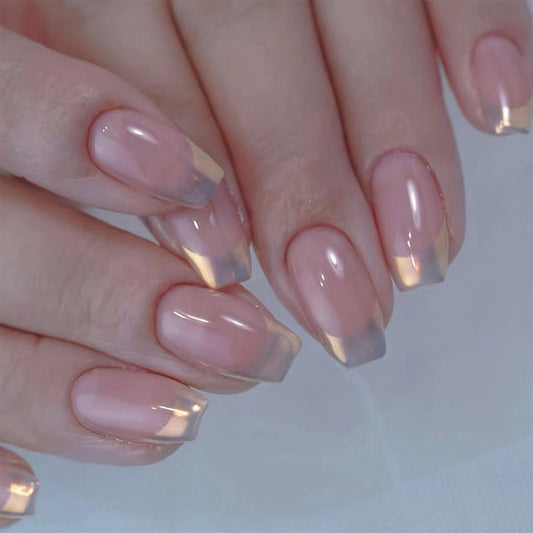 Close-up of hands with pink and gold gradient nail polish on a light background