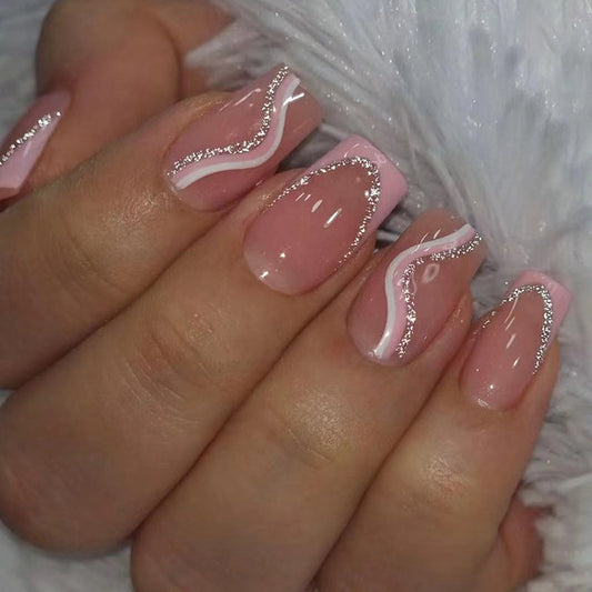 Hand with pink nails and silver glitter designs on a neutral background