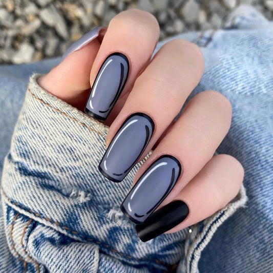 A pair of long square press-on nails with a smokey grey color and glossy black tips, displayed on a hand.