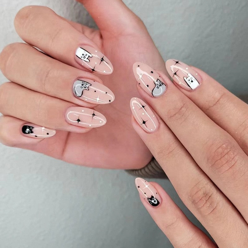 A pair of hands showcasing press-on nails with a beige base and cartoon cat designs.