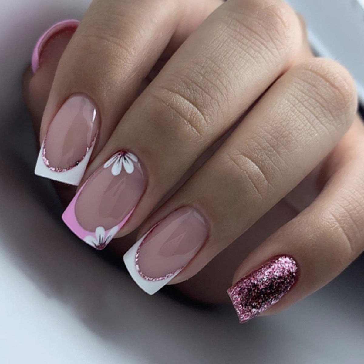 Close-up of a hand with pink and white floral nail design on a neutral background