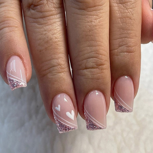 Close-up of a hand with pink and white nail design on a neutral background