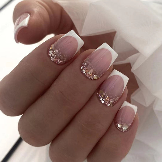 Hand with pink nails with glitter and white tips against a blurred background