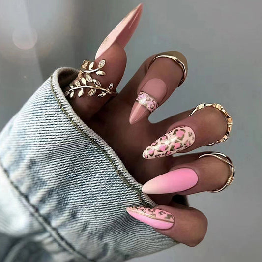 Hand with pink and gold nail art wearing denim sleeve