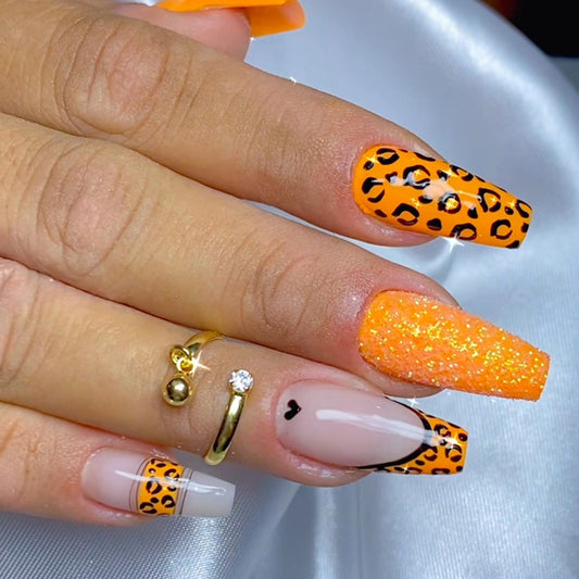 A hand with medium-sized, orange leopard print false nails.