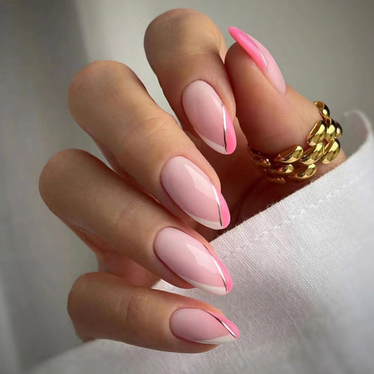 Hand with pink and white gradient nails wearing a gold ring on a neutral background
