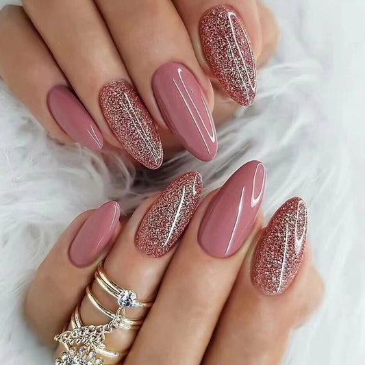 A pair of medium length oval-shaped nails with a pink glitter design.