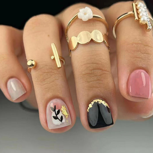 Close-up of a hand with decorative nail art and gold rings.