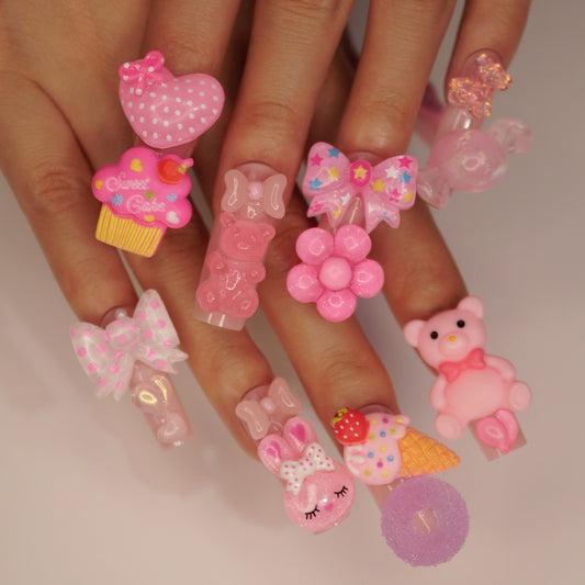 Fingers with decorative nail art featuring pink and clear designs on a neutral background