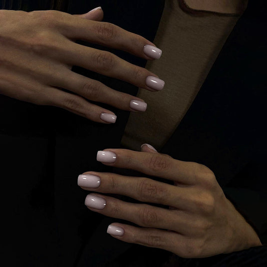 A pair of short square-shaped, soft pink press-on nails with a glossy finish.