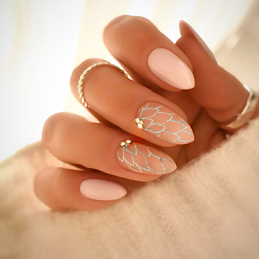 Close-up of a hand with almond-shaped nails featuring a decorative design on a neutral background