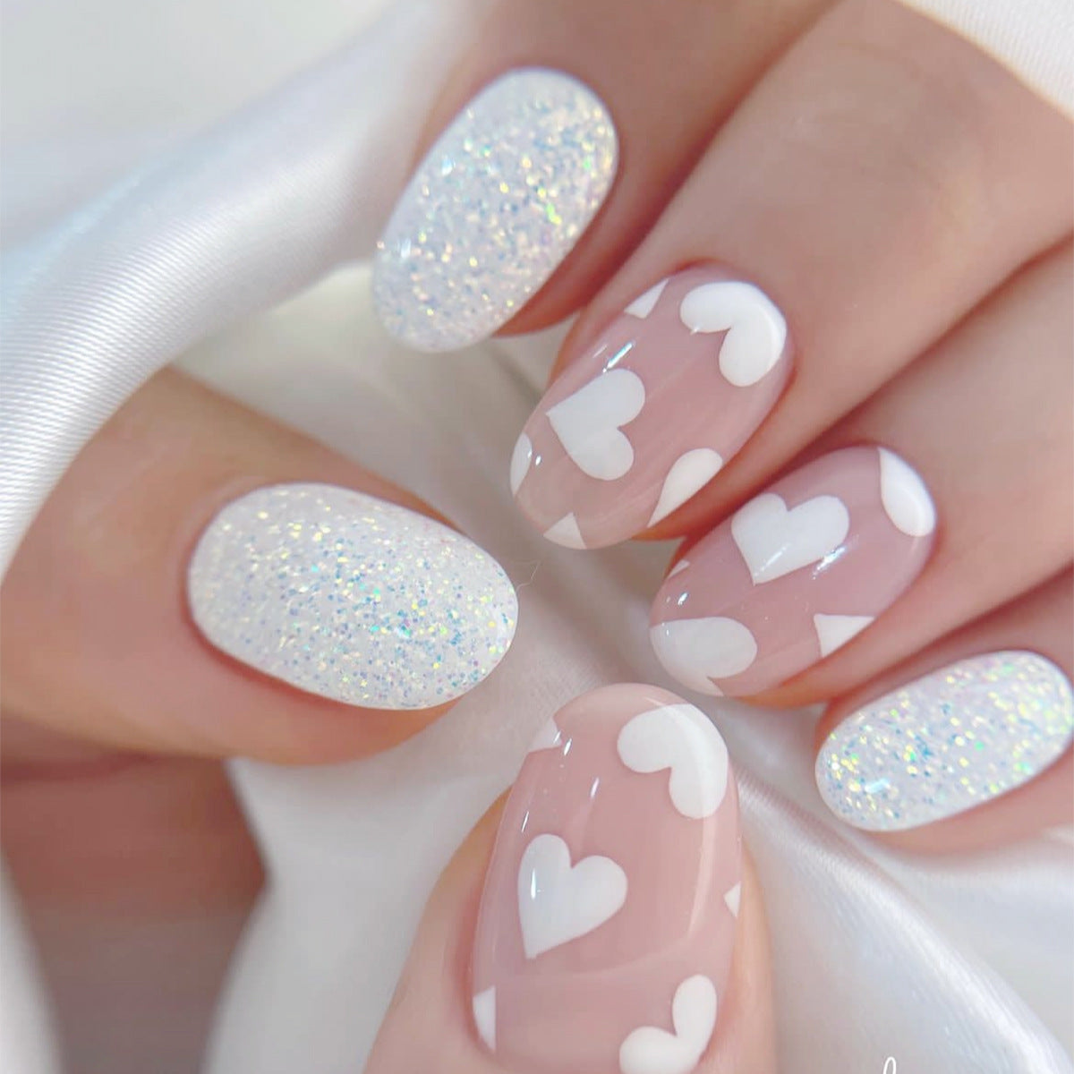 Nails with pink and white heart design on a white background